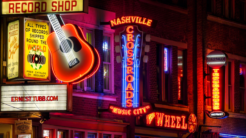 Nashville Broadway with neon record shop signs and music venue lights at night showcasing Music City's famous entertainment district